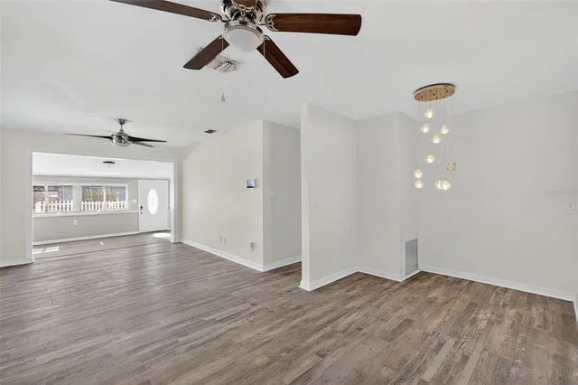 a view of empty room with wooden floor and ceiling fan