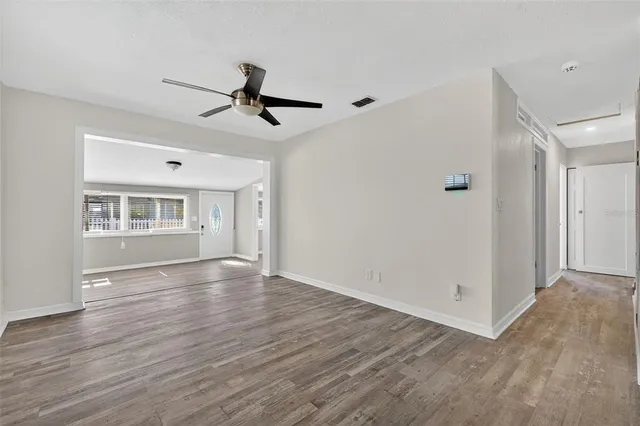 a view of an empty room with wooden floor and a window