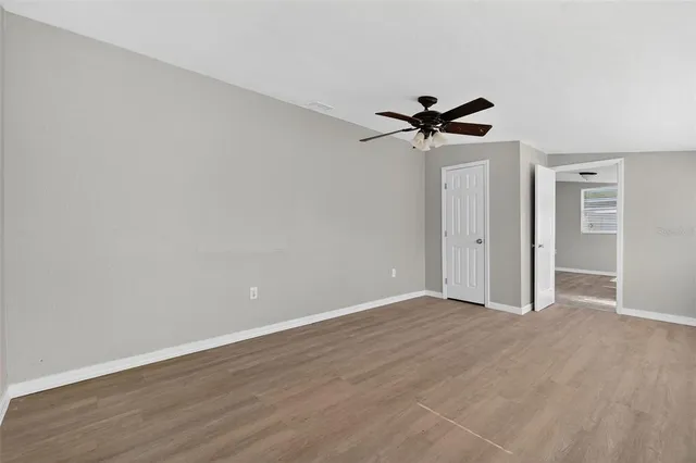 an empty room with wooden floor and ceiling fan