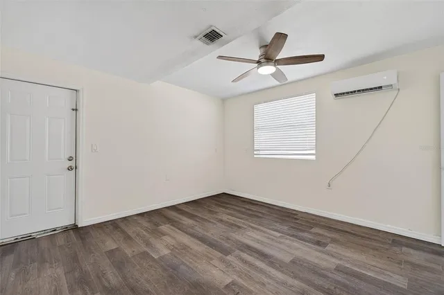 an empty room with wooden floor ceiling fan and window