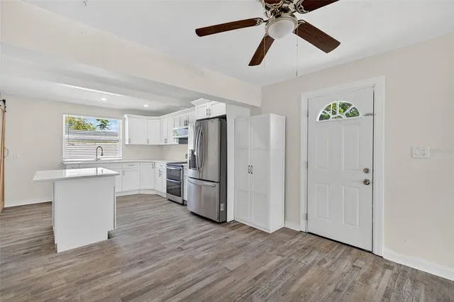 a view of an empty room with wooden floor and a ceiling fan