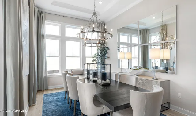 a dining room with wooden floor a chandelier a glass table and windows