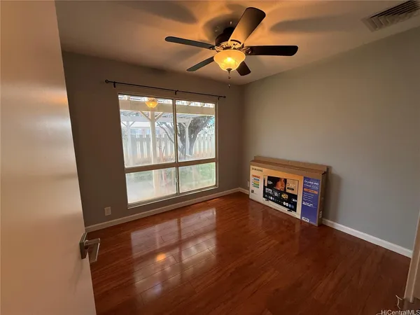 an empty room with wooden floor and windows