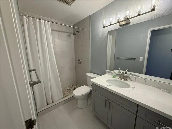 a bathroom with a sink a toilet a mirror and shower curtain