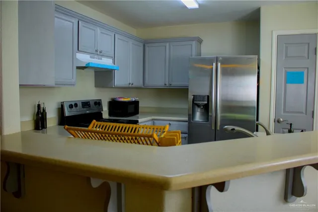 a kitchen with stainless steel appliances granite countertop a sink a refrigerator and a white cabinets