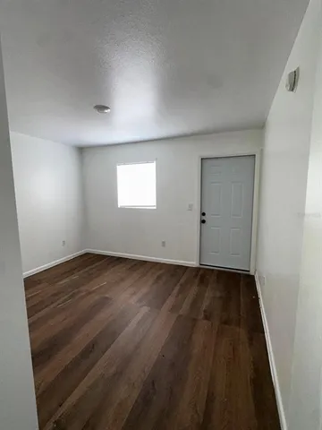 an empty room with wooden floor and window
