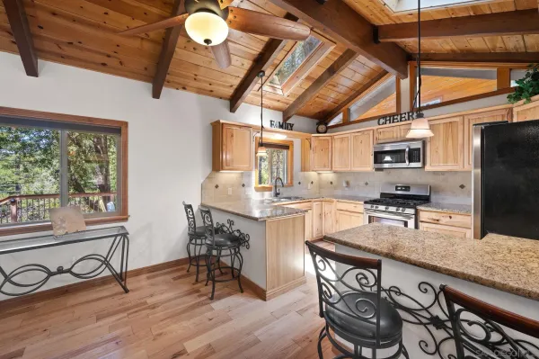 a kitchen with granite countertop a stove a sink dishwasher a dining table and chairs with wooden floor
