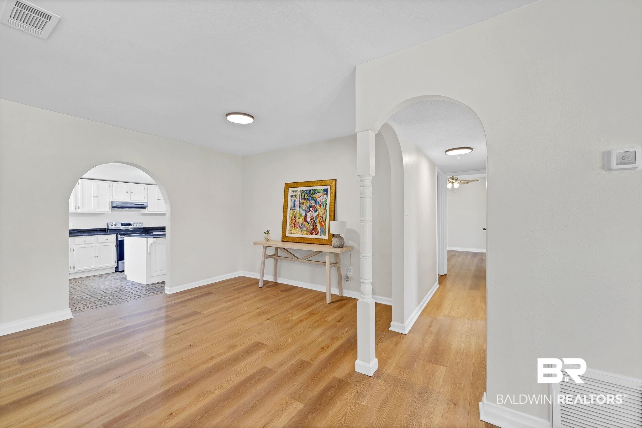 11964 Stroh Road Daphne, AL 36527 - Photo 16 of 58 Corridor featuring visible vents, light wood-style flooring, arched walkways, and baseboards