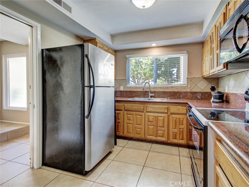 1881 Mitchell Avenue, Unit 63 Tustin, CA 92780 - Photo 6 of 24 a kitchen with stainless steel appliances granite countertop a refrigerator and a sink