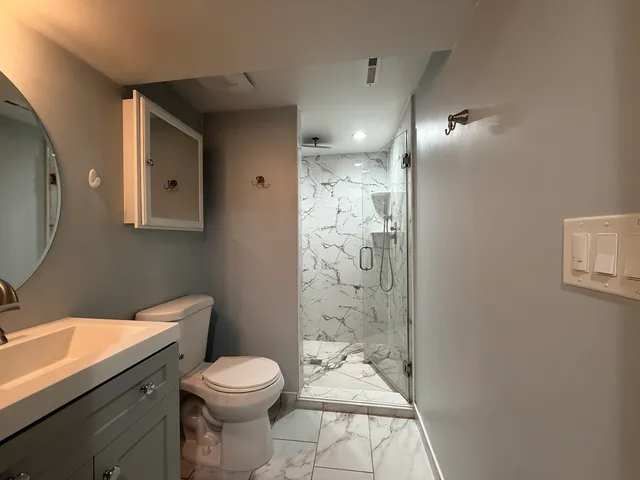 a bathroom with a granite countertop toilet a sink a mirror and shower
