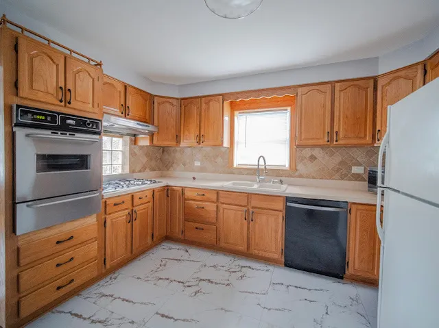 a kitchen with granite countertop a sink stainless steel appliances and window