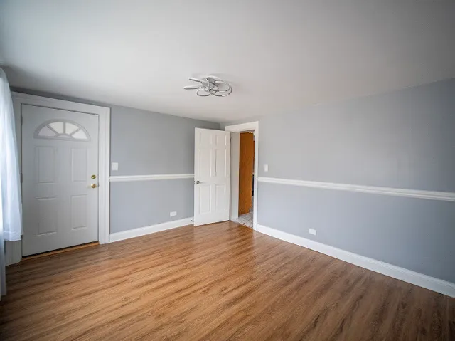 a view of an empty room with wooden floor and closet