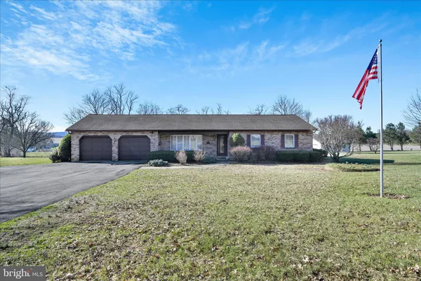 a front view of house with yard and trees in the background