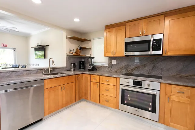 a kitchen with stainless steel appliances granite countertop a stove microwave and sink