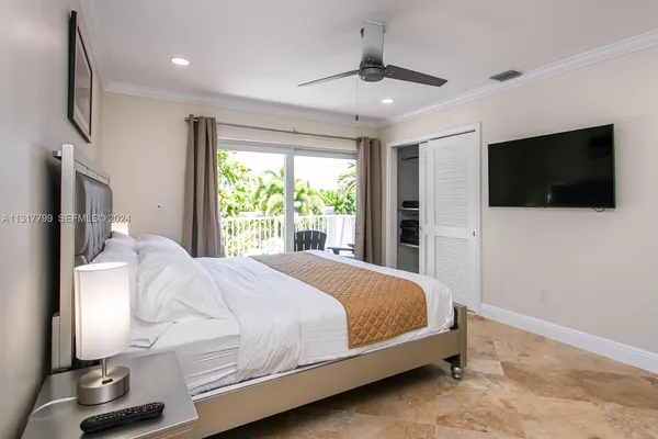 a bedroom with a bed tv and a window
