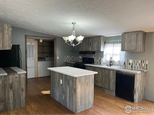 a kitchen with stainless steel appliances granite countertop a stove a refrigerator a sink dishwasher and a dining table with wooden floor
