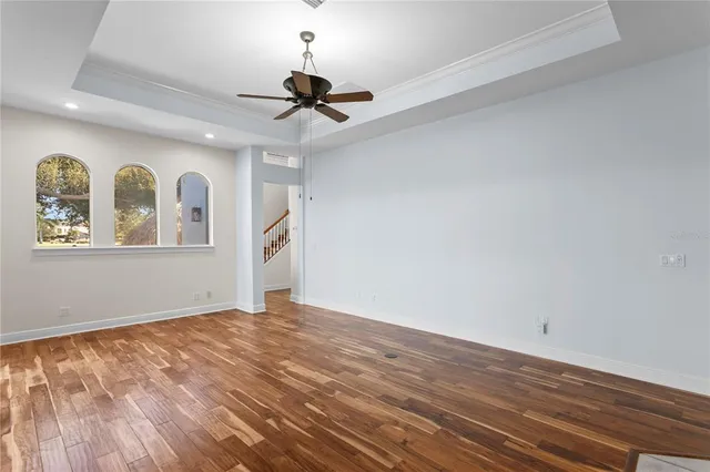 an empty room with wooden floor and fan