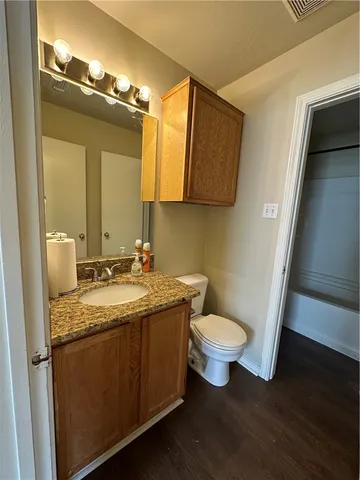 a bathroom with a granite countertop sink a toilet and a mirror