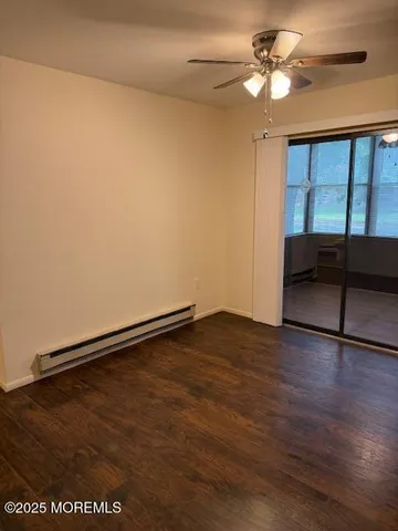 an empty room with wooden floor fan and windows