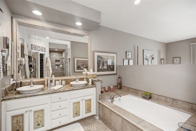a bathroom with a granite countertop tub sink and mirror