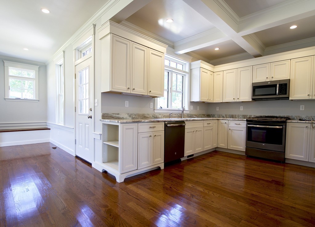 180 First Parish Road Scituate, MA 02066 - Photo 10 of 26 a kitchen with stainless steel appliances white cabinets a sink a stove a microwave and wooden floors