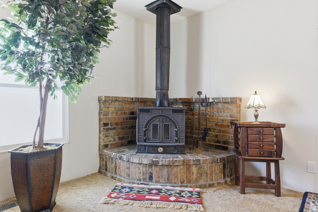 365 North Main Street Fillmore, UT 84631 - Photo 24 of 51 Corner wood-burning stove set on a raised brick hearth with a matching brick surround