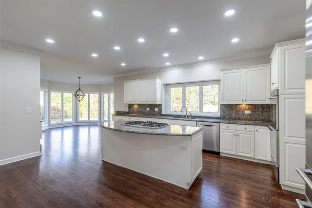 a kitchen with kitchen island granite countertop wooden floors and white cabinets