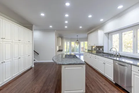 a kitchen with center island wooden floor and stainless steel appliances