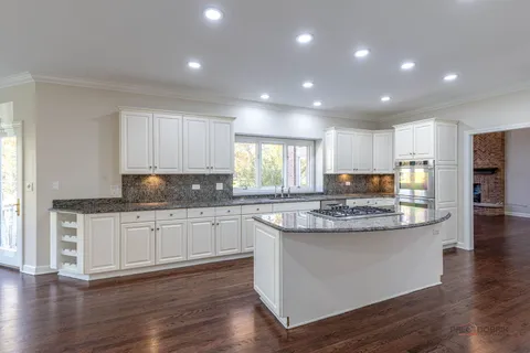 a kitchen with stainless steel appliances granite countertop wooden floor and window