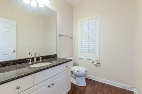 a bathroom with a granite countertop sink toilet and mirror