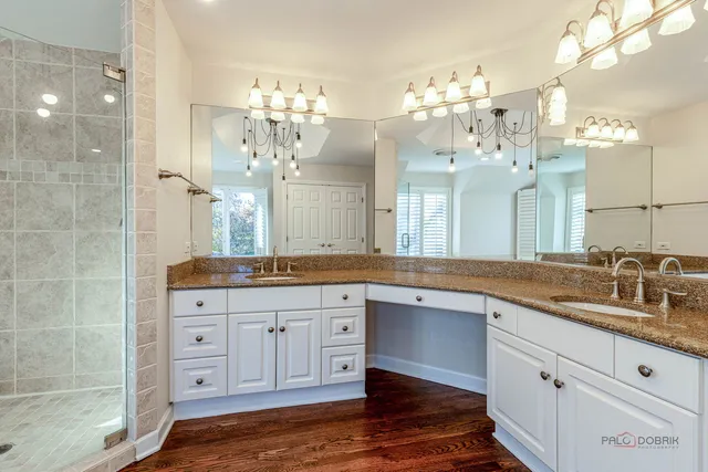 a spacious bathroom with a granite countertop sink a large mirror and a shower