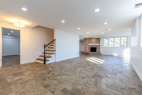 an empty room with windows and fireplace