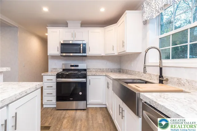 a kitchen with granite countertop a stove a sink and a microwave