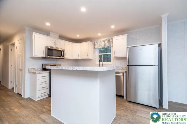 a kitchen with kitchen island a refrigerator and a sink