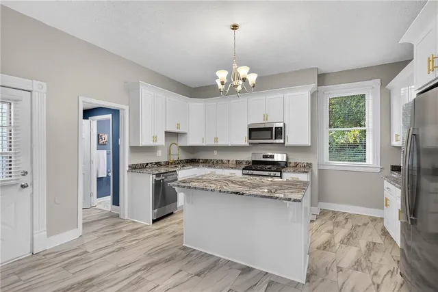 a kitchen with stainless steel appliances granite countertop a stove top oven a refrigerator a sink and dishwasher with wooden floor