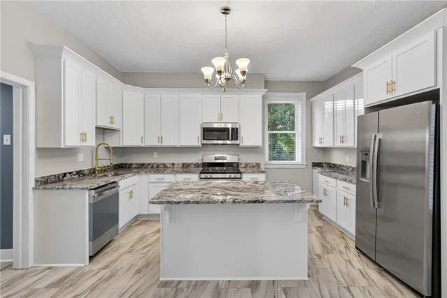 a kitchen with kitchen island granite countertop stainless steel appliances a stove refrigerator sink and microwave
