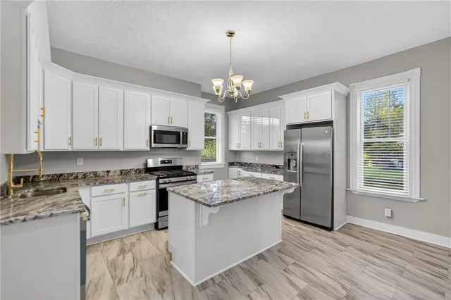 a kitchen with stainless steel appliances granite countertop a stove top oven a refrigerator a sink and dishwasher with wooden floor