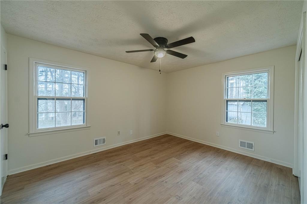 1678 Pounds Road Southwest Stone Mountain, GA 30087 - Photo 18 of 25 an empty room with wooden floor ceiling fan and windows