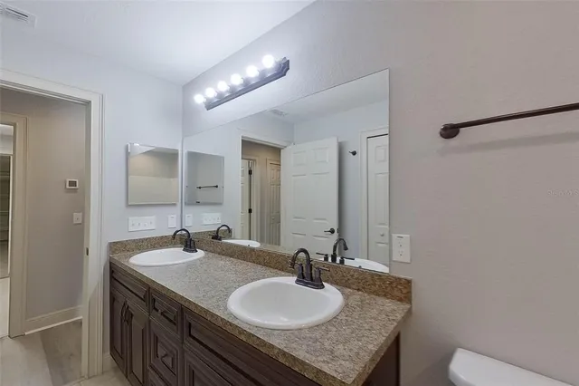 a bathroom with a granite countertop sink a toilet and a mirror