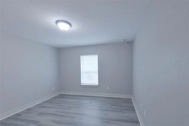 a view of an empty room with wooden floor and window