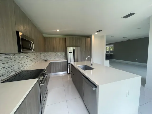 a large kitchen with a large counter top a sink a stove and a refrigerator