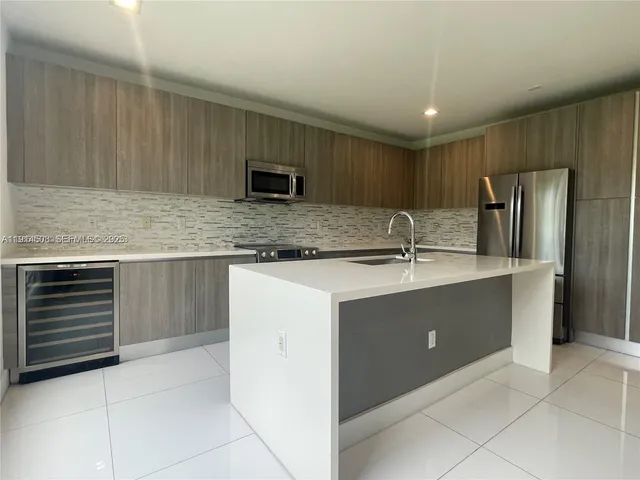 a kitchen with stainless steel appliances granite countertop a sink and a refrigerator