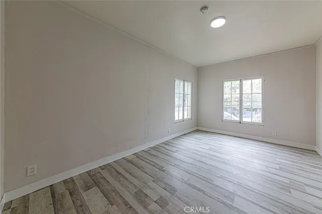 a view of a hallway with wooden floor and a bathroom