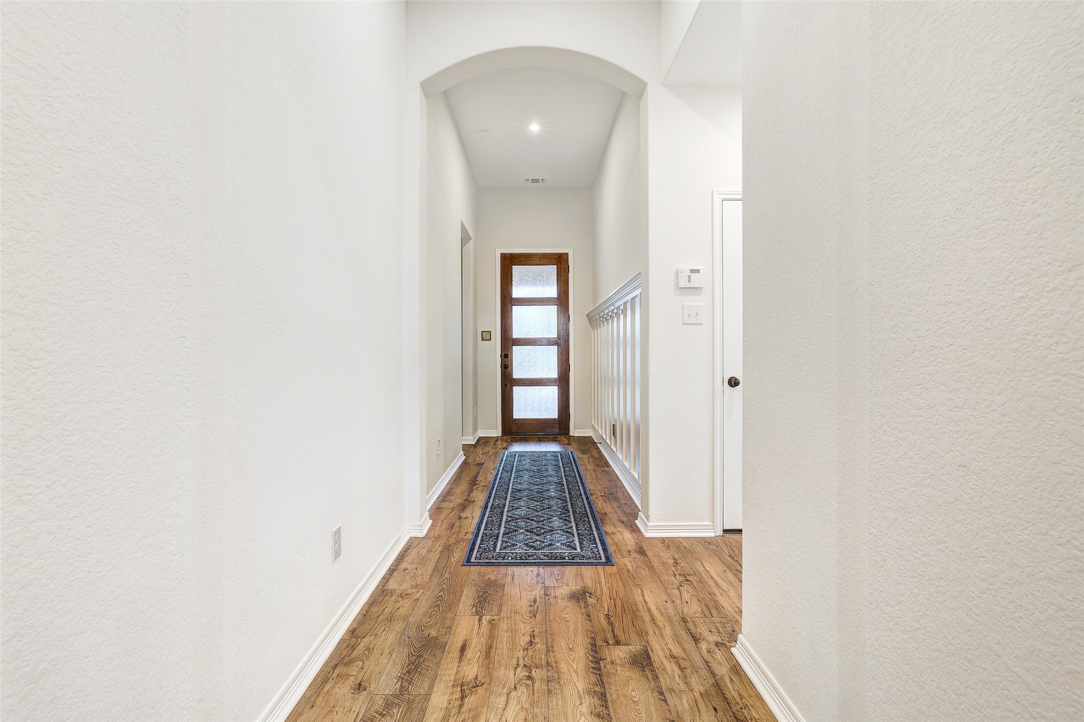 1117 Spring Gulch Lane Georgetown, TX 78628 - Photo 10 of 39 A welcoming entry hall with hardwood flooring and an arched doorway leading to an elegant front door.