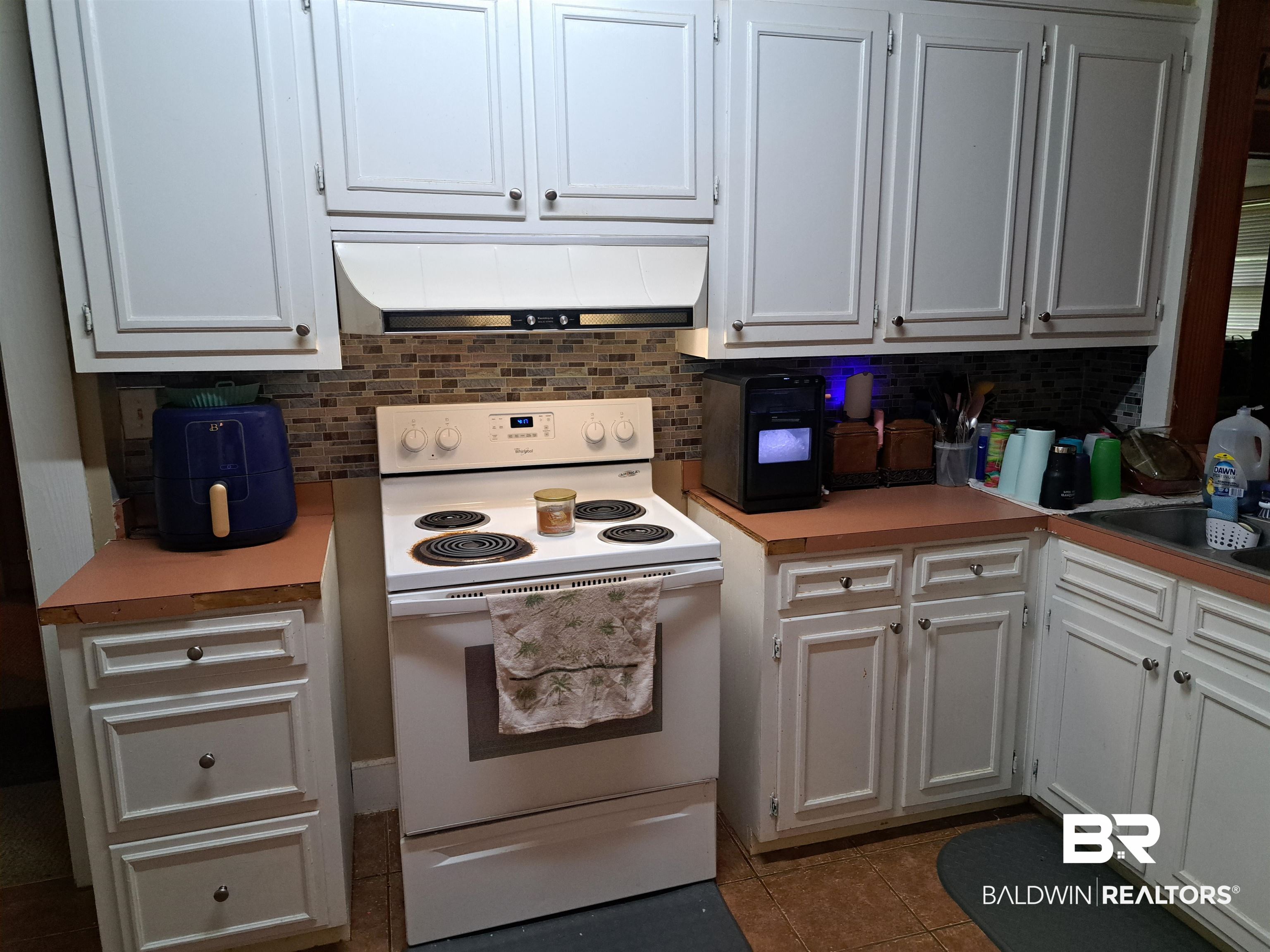309 Bellview Avenue Evergreen, AL 36401 - Photo 11 of 27 Kitchen with white range with electric cooktop, white cabinetry, under cabinet range hood, light countertops, and dark tile patterned floors