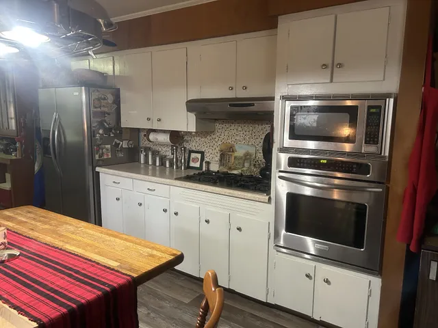 a kitchen with stainless steel appliances kitchen island granite countertop a stove a sink and a refrigerator