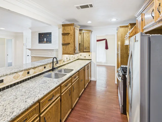 a large kitchen with granite countertop a sink and refrigerator