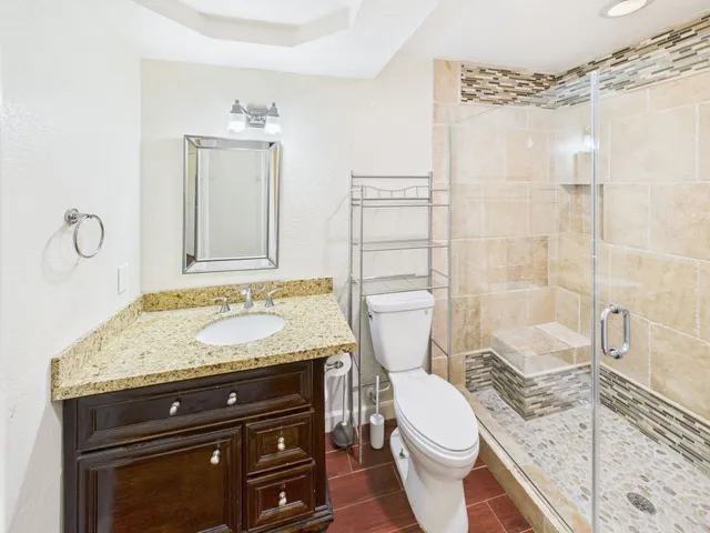 a bathroom with a granite countertop toilet sink and mirror