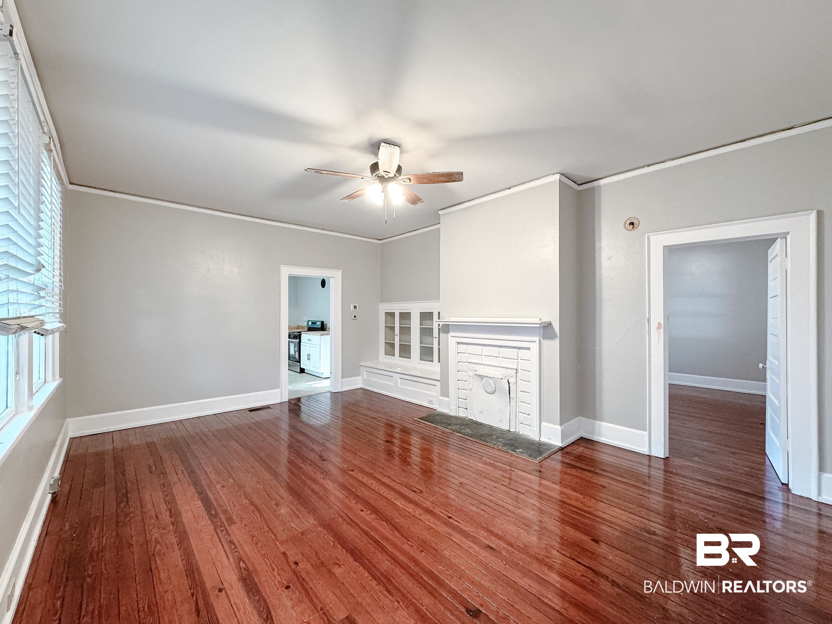 206 1st Street Mobile, AL 36611 - Photo 7 of 26 Unfurnished living room with crown molding, a fireplace, dark wood-style flooring, and a ceiling fan