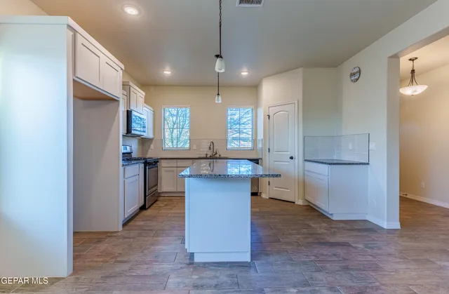 a kitchen with stainless steel appliances granite countertop a stove a sink and a microwave